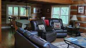 Ein gemütliches Blockhaus-Interieur mit Essbereich, Ledersofas und einem Kronleuchter.