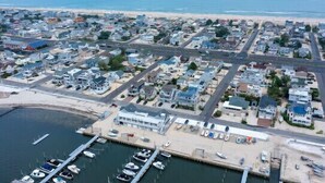 Vue aérienne d’une ville côtière avec un port de plaisance, des zones résidentielles et une plage.