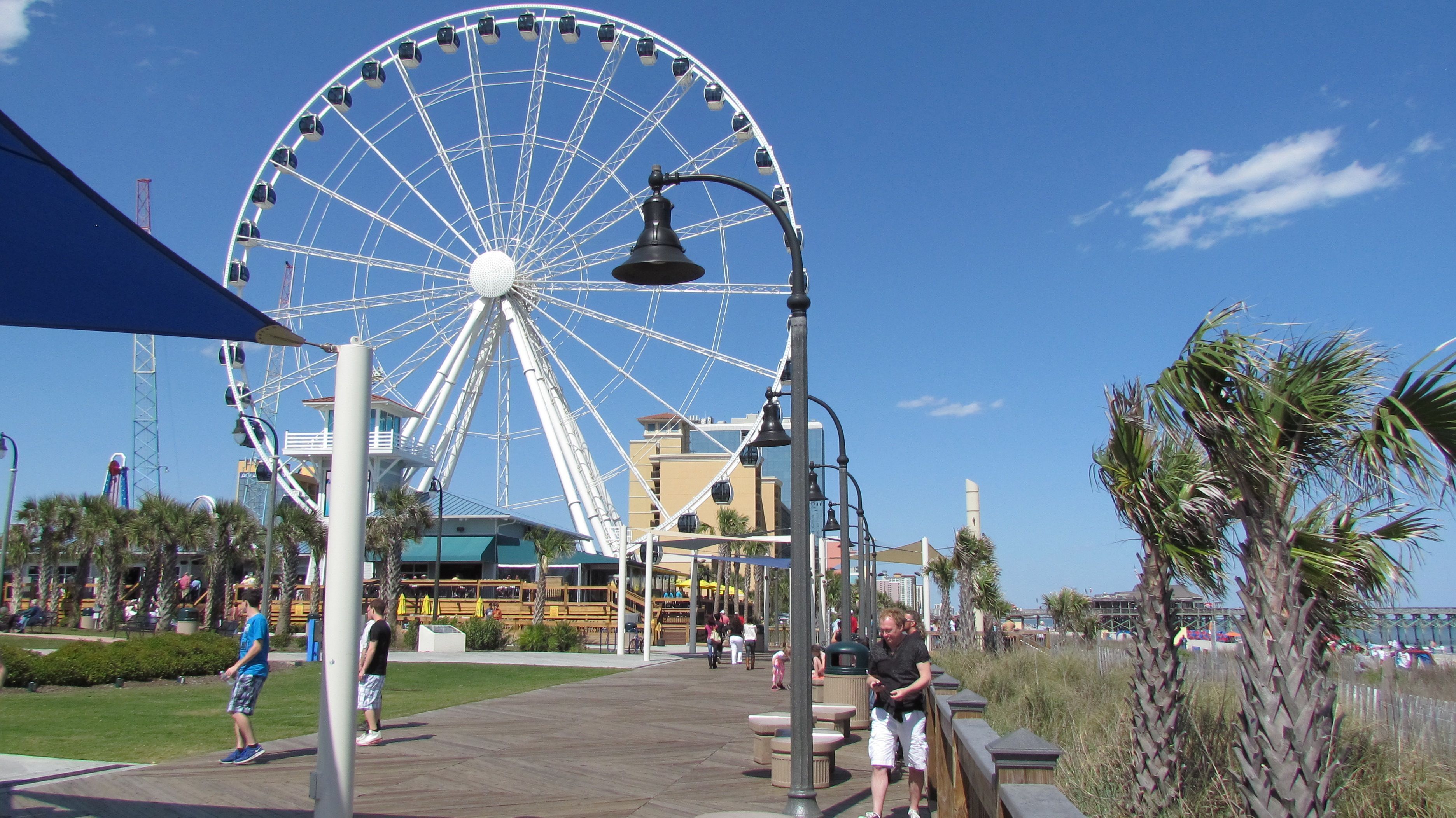 A Ferris wheel, a boardwalk, and a building with a balcony.