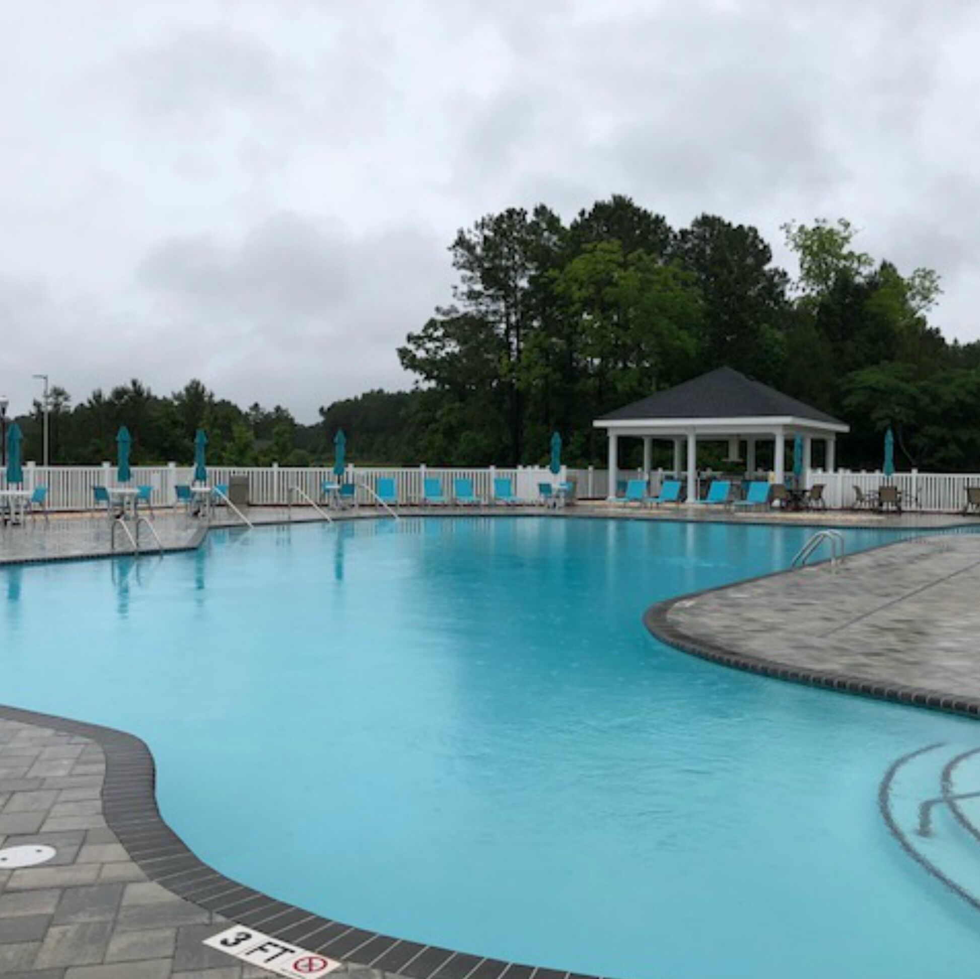A swimming pool with lounge chairs and a gazebo.