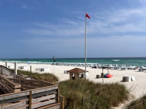 Relax on the beach with comfortable lounge chairs and umbrellas, surrounded by calm ocean waves.