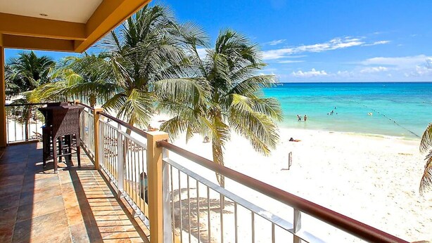 Un balcon avec vue sur une plage et des palmiers.