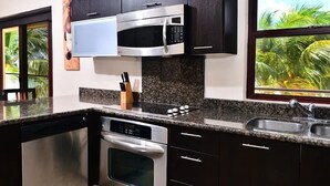 Une cuisine moderne dotée d’appareils électroménagers en acier inoxydable, de plans de travail en granit et de meubles de rangement aux couleurs sombres.