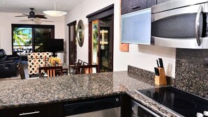 Une cuisine moderne dotée de plans de travail en granit, d’appareils électroménagers en acier inoxydable et d’un coin repas avec une nappe à pois.