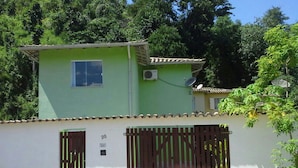 A two-story building with a green facade, a small window on the upper floor, and a gated entrance with a number '20' sign. - Casa Verde Paraty (Paraty)