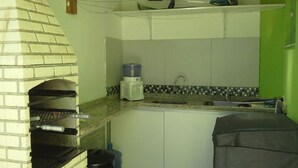 A kitchen with a built-in brick oven, a water dispenser, and a sink with a tiled backsplash. - Casa Verde Paraty (Paraty)