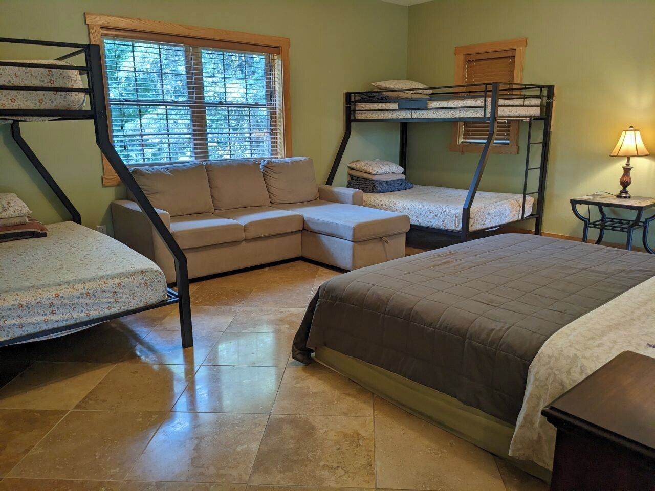 A room with bunk beds, a sofa, and a lamp.