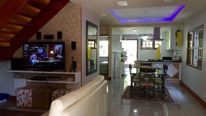 Ein modernes Wohnzimmer mit einem weißen Sofa, einem Fernseher und einer Treppe.
