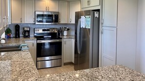 A modern kitchen with stainless steel appliances, white cabinetry, and granite countertops. - Westbay Point Moorings 214 2 Bedroom Condo by RedAwning (Holmes Beach)