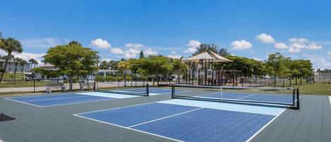 An outdoor tennis court with a gazebo and seating area.