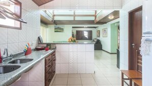 Una cocina con dos fregaderos, techo de madera y vista al área de estar.