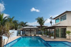 Una piscina al aire libre, sombrillas, sillones reclinables de piscina