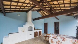 Una habitación con piso de baldosas, una mesa cubierta con mantel, una chimenea y puertas de madera.