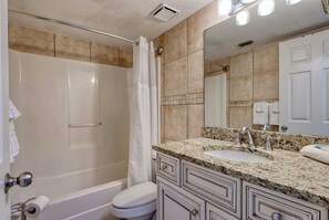 Un baño con ducha, inodoro, lavamanos y tocador.