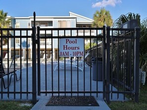 A gated pool area with a sign indicating pool hours from 8AM to 10PM. - Sea Oats H102 2 Bedroom Condo by RedAwning (Gulf Shores)