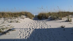 A sandy pathway leading to a beach with tall grasses on either side. - Sea Oats H102 2 Bedroom Condo by RedAwning (Gulf Shores)