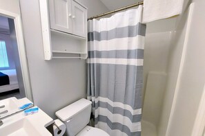 Ein Badezimmer mit Toilette, einem weißen Schrank und einem gestreiften Duschvorhang.