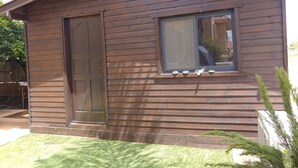 A wooden house with a large door, a window with blinds, and a small porch area. - Assaf's Cabin (Mateh Asher)