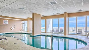 An indoor swimming pool with clear views of the cityscape through large windows. - Lighthouse 1017 1 Bedroom Condo by RedAwning (Gulf Shores)