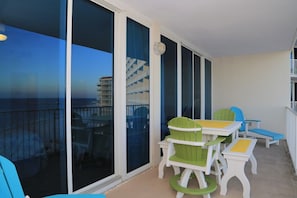 A balcony with a table and chairs, large glass doors, and a view of a building across the water.