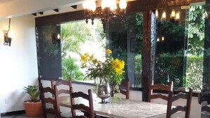 Un comedor con una mesa grande, seis sillas de madera y un jarrón con flores amarillas.