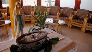 A room with wicker chairs, a statue, and a table with a bowl. - St. Vincent Guest House - Bethlehem (Bethlehem)