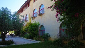 A building with multiple arched windows, some with red railings, and a courtyard with outdoor seating. - St. Vincent Guest House - Bethlehem (Bethlehem)