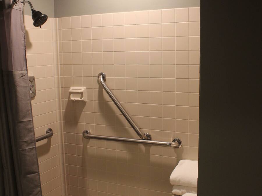 A shower area with a grab bar, a towel rack, and a shower curtain.