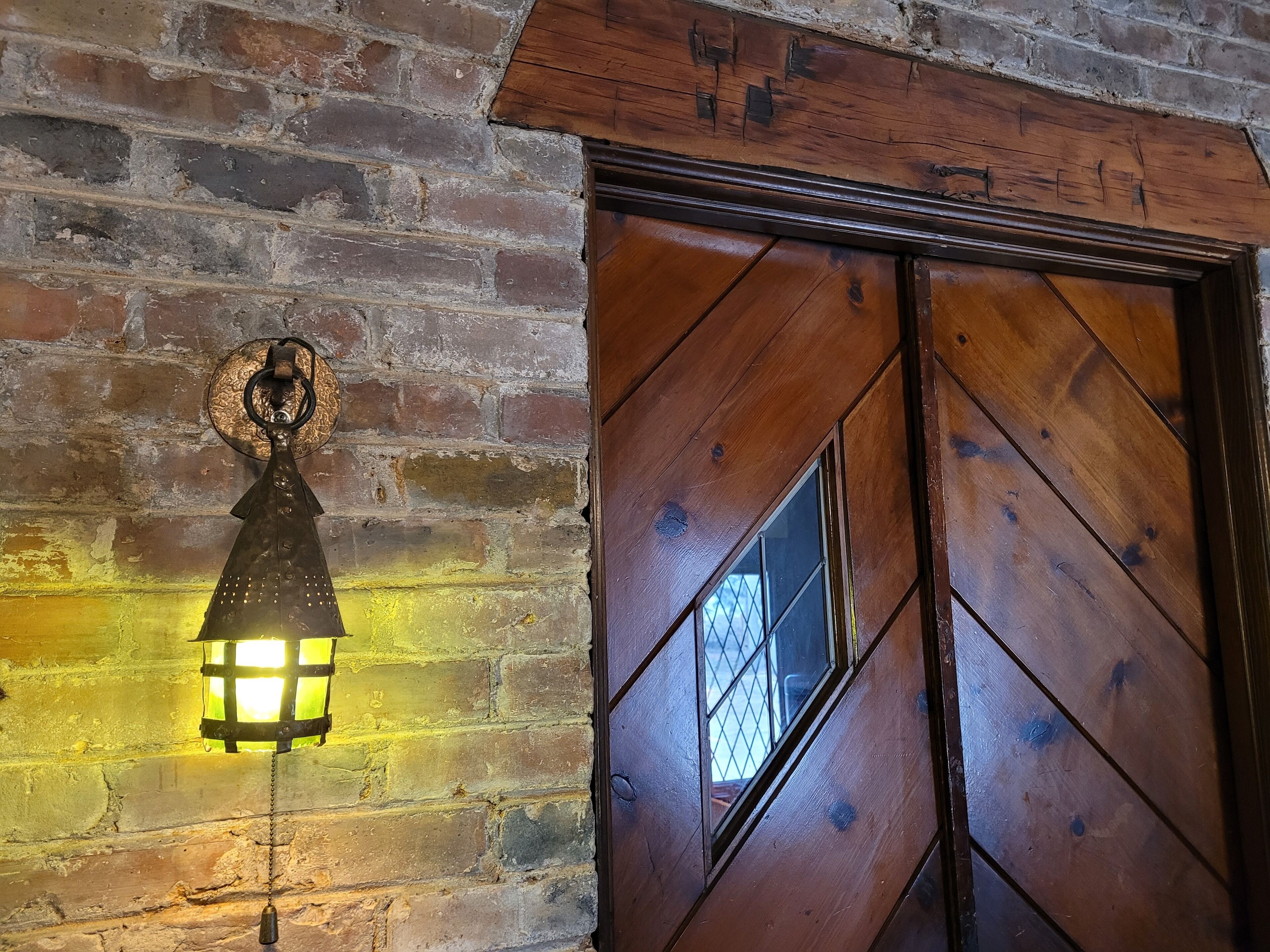 Une porte en bois ornée d’un motif en losanges et dotée d’une petite fenêtre.