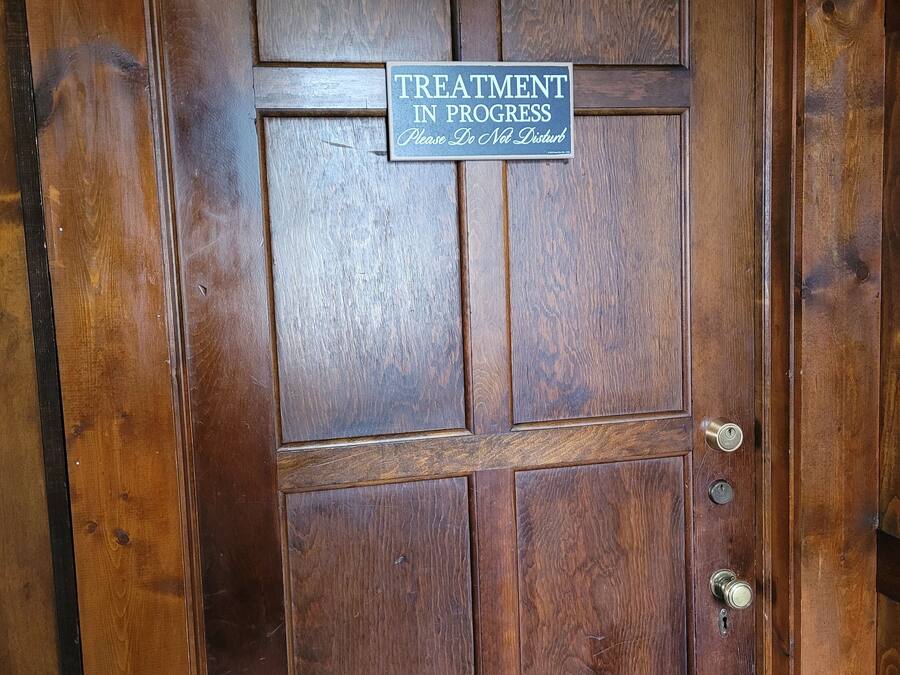 Una puerta de madera con un cartel que dice 'TRATAMIENTO EN CURSO No molestar'.