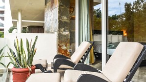 A modern outdoor seating area with a potted plant and a glass door leading to a room. - Mamitas Village by Casago (Playa del Carmen)