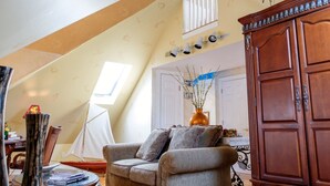 Un salón acogedor con techo inclinado, un armario de madera, un sofá y un jarrón decorativo.