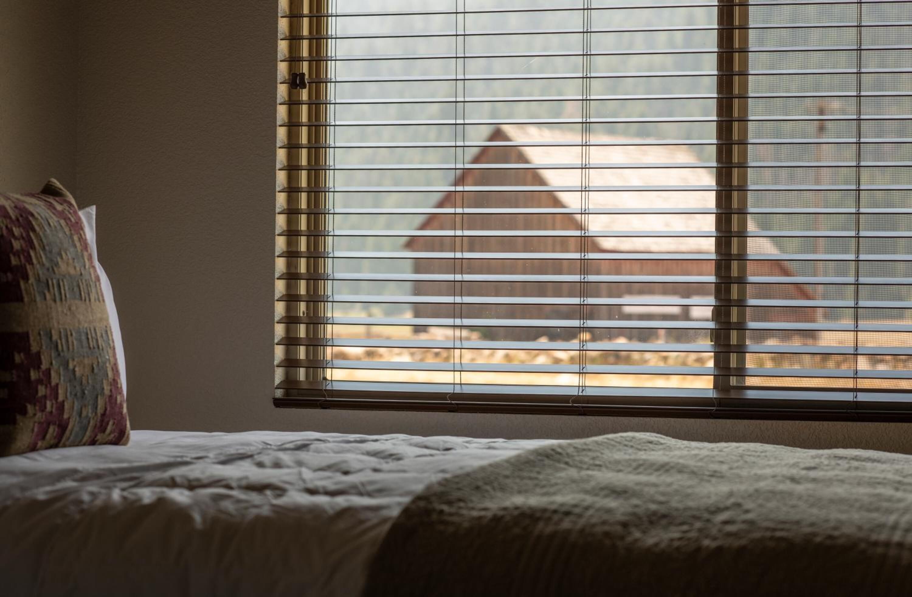 Camera da letto con un letto, una finestra con persiane e vista su un edificio.