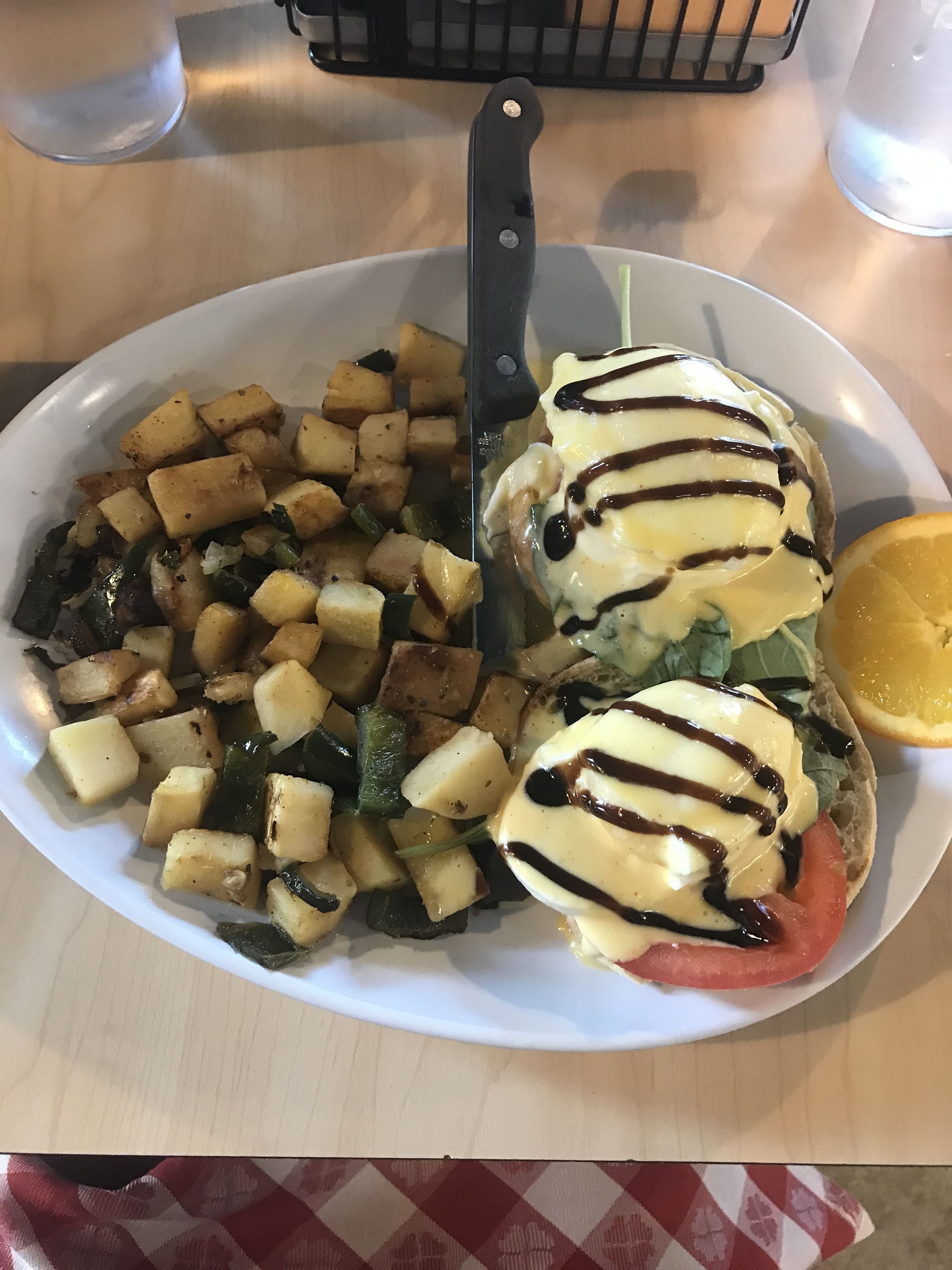 A plate of food with roasted potatoes, a slice of tomato, and a piece of bread topped with sauce.
