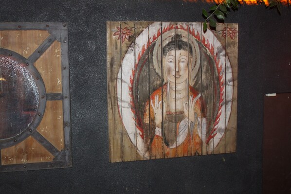 Una pared con dos paneles: uno con un diseño metálico circular y otro con una pintura tradicional.