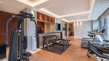 Une salle de sport moderne équipée de matériel d’exercice, d’un téléviseur et d’un espace détente agrémenté d’une plante.