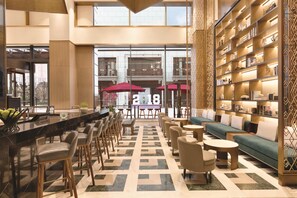 A modern hotel lobby with a bar area, seating, and a bookshelf. - Hyatt House Chengdu Pebble Walk (Chengdu)