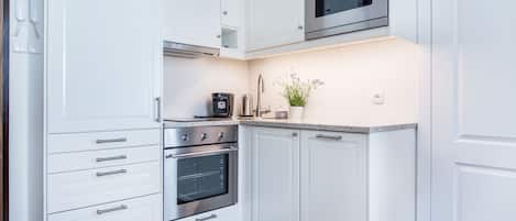 Una cocina moderna con armarios blancos, electrodomésticos de acero inoxidable y horno empotrado.