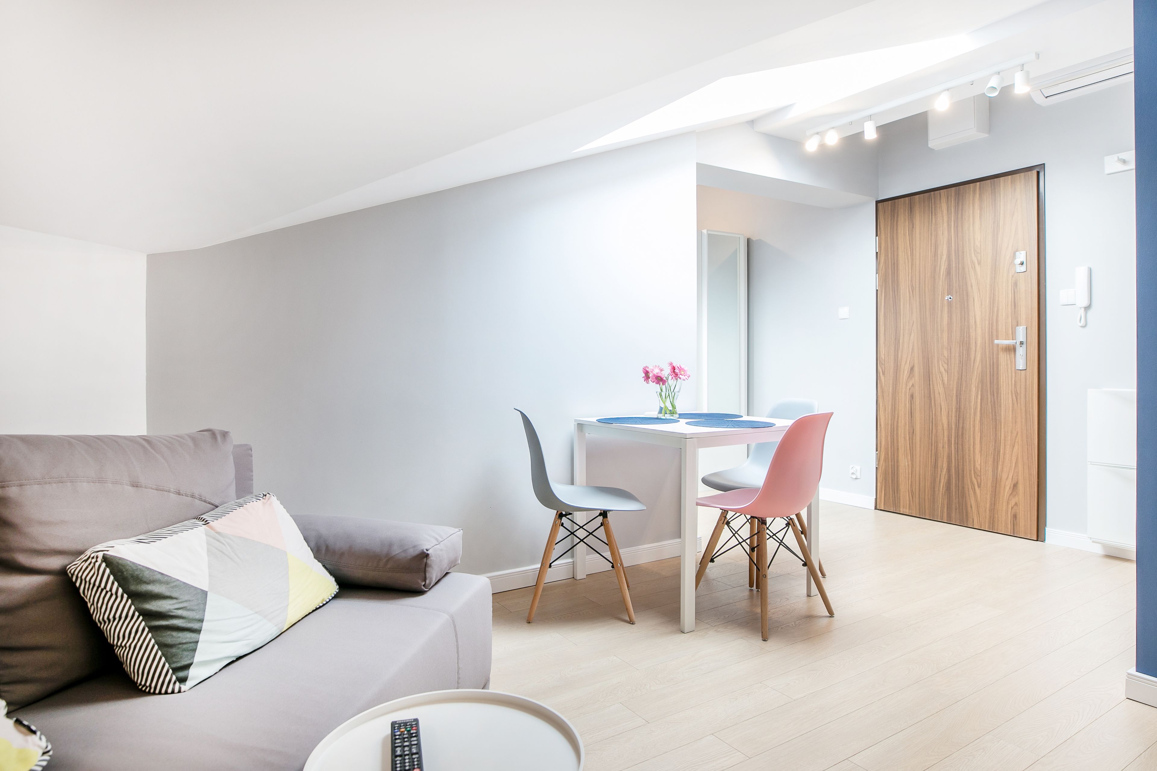 Een moderne woonkamer met een bank, een eettafel met stoelen en een houten deur.