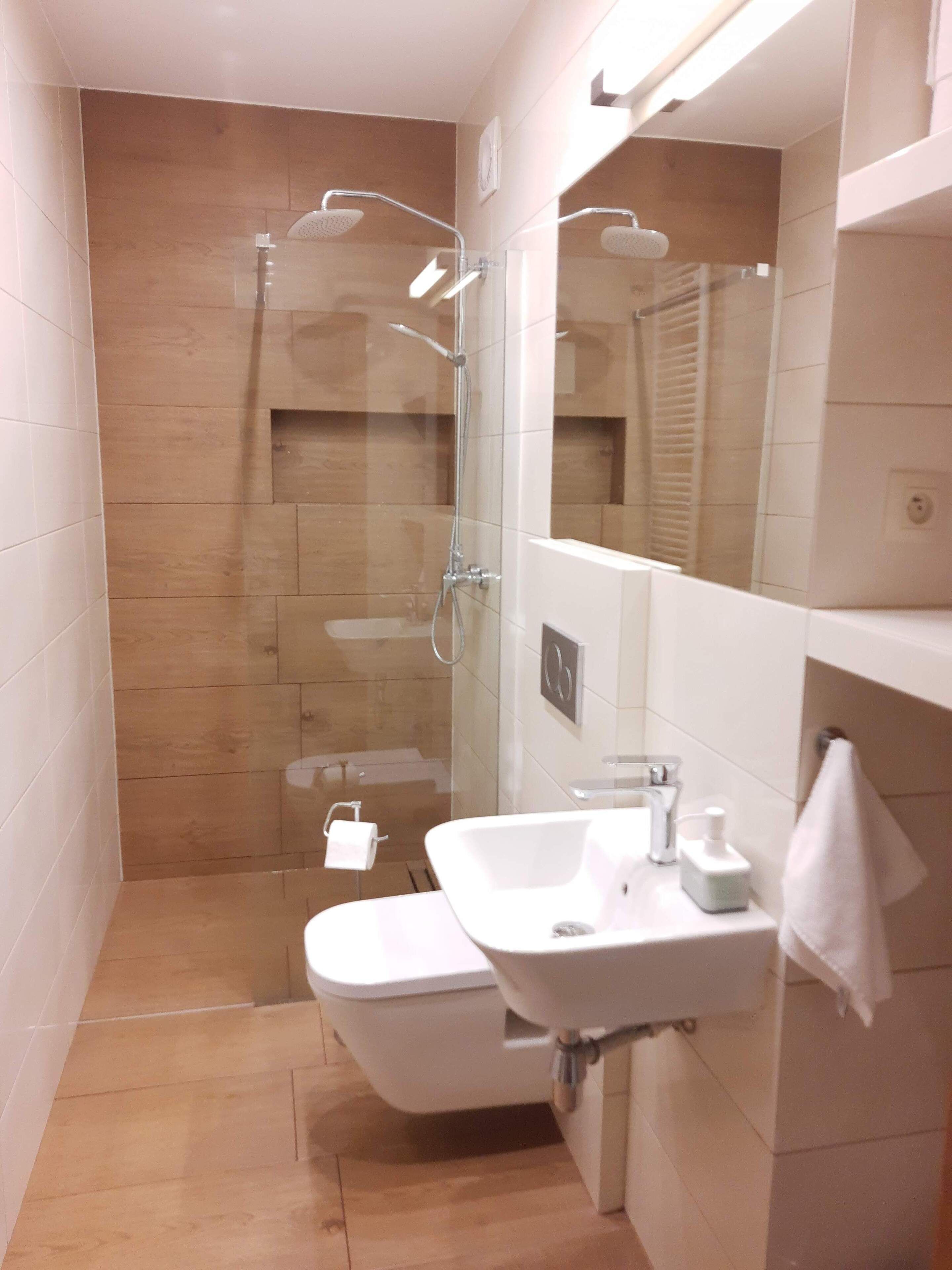 A modern bathroom with a glass-enclosed shower, a white sink, and a mirror.