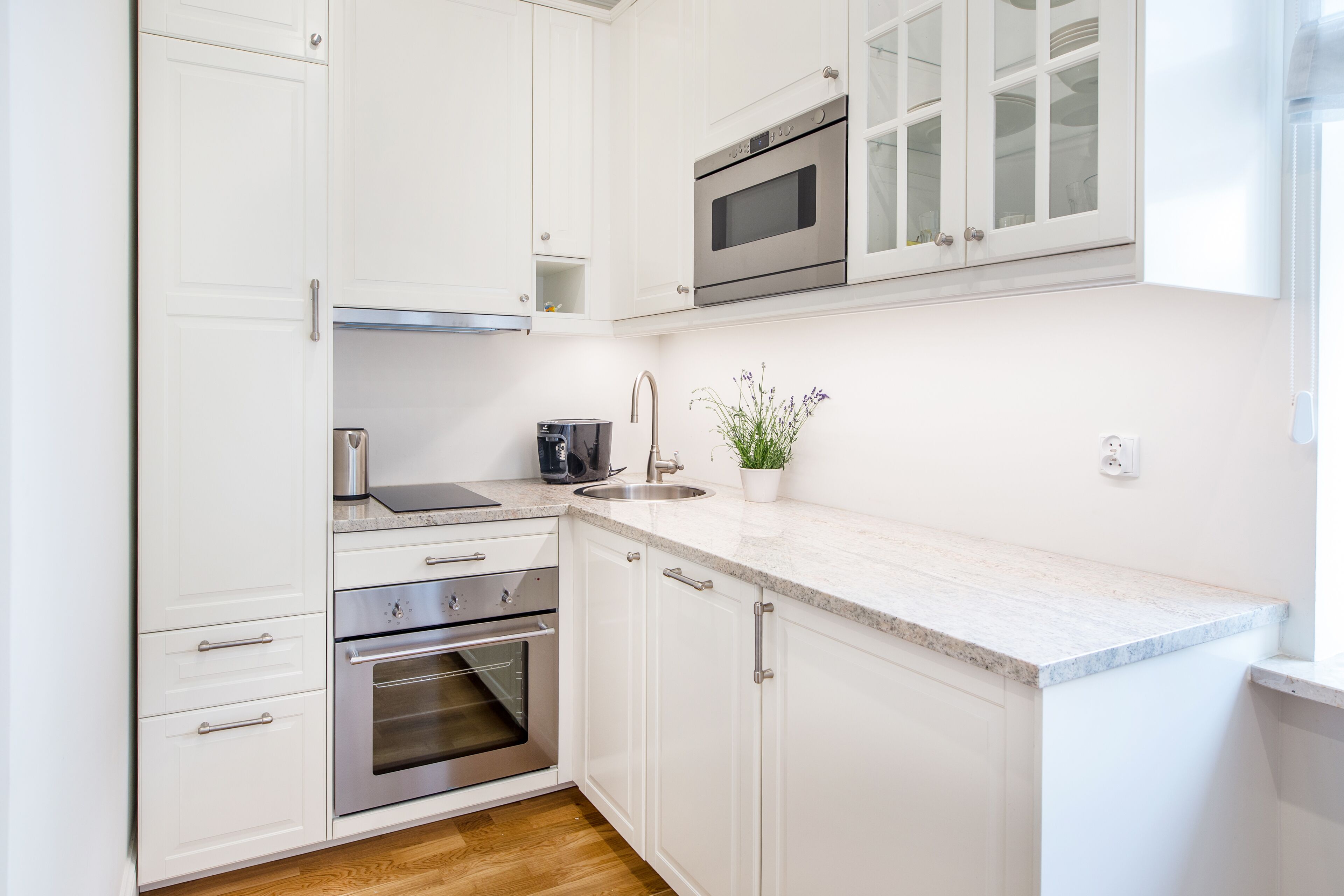 Una cocina moderna con armarios blancos, electrodomésticos de acero inoxidable y encimera de mármol.