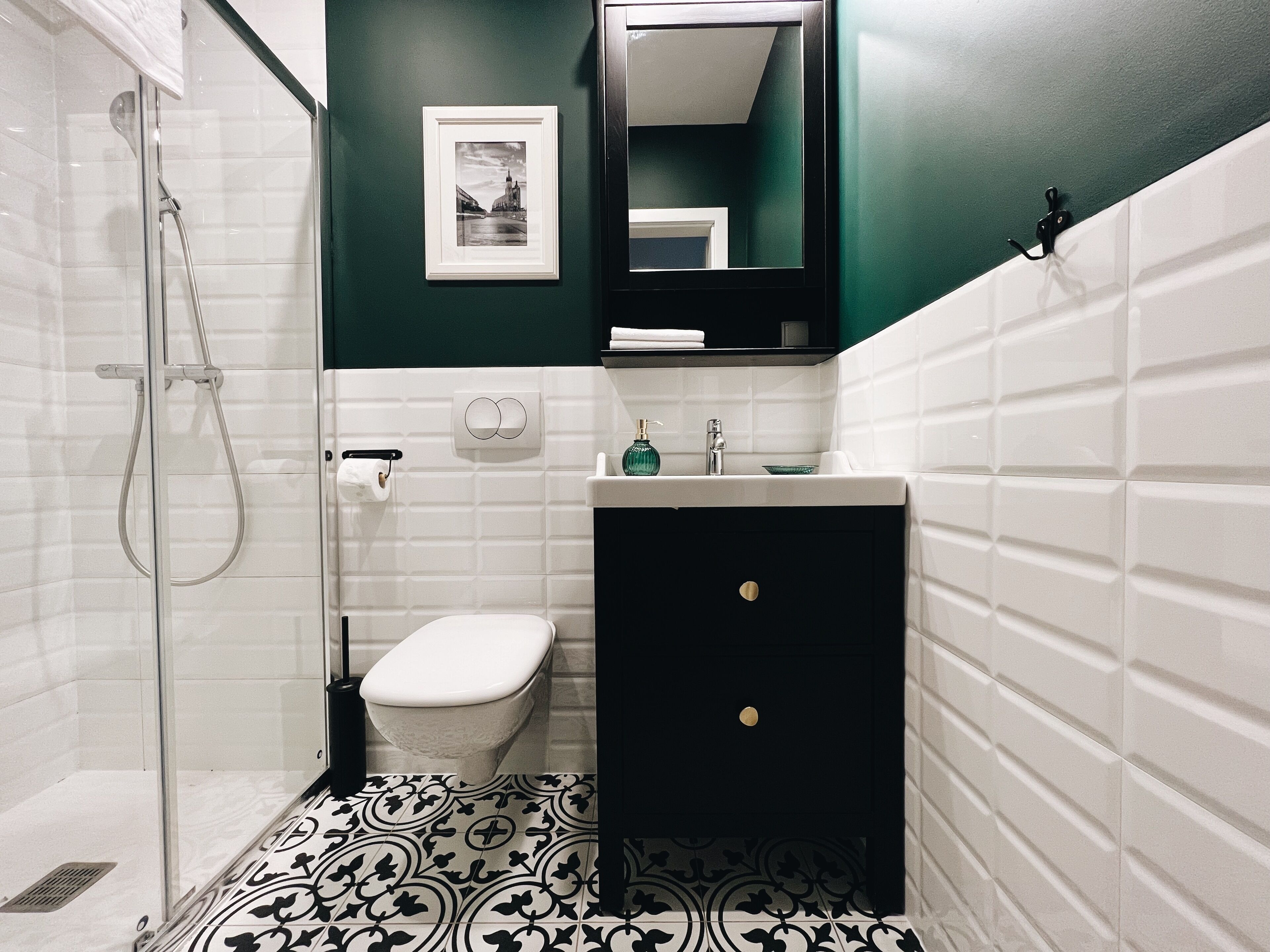 Un baño con ducha, inodoro, lavamanos y un espejo sobre el lavamanos.