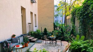 Un patio con zona de estar, plantas en macetas y un sendero de grava.