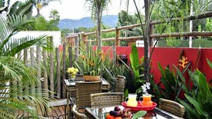 An outdoor dining area with wicker furniture, a fruit tray, and a beverage. - Pousada Cana Caiana (Paraty)