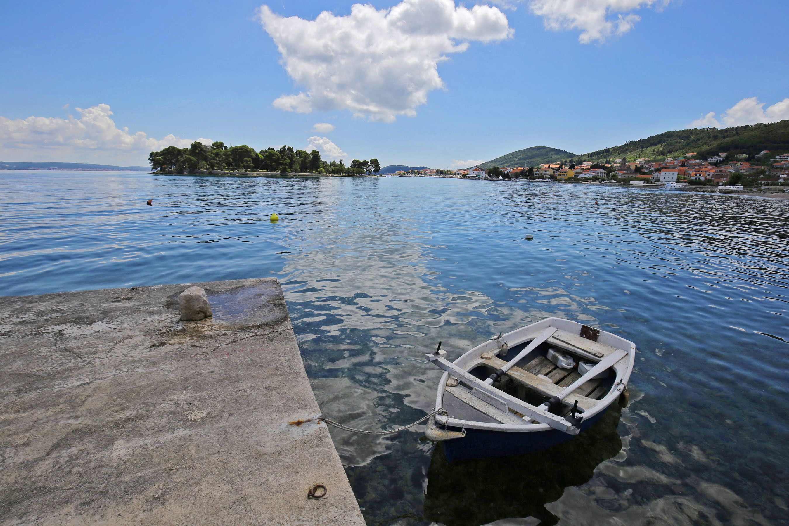 Un lago tranquilo con una pequeña embarcación amarrada a un muelle de hormigón.