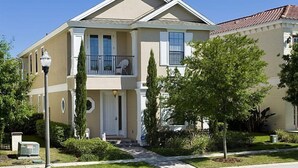 Une maison à deux étages avec un porche à l’avant, un balcon et une pelouse bien entretenue.