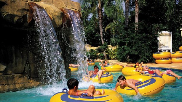 Un parc aquatique avec des personnes sur des bouées jaunes et une cascade.
