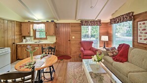 Ein gemütliches Blockhaus-Interieur mit einem Holzesstisch, einer Couch, einem roten Sessel und einer Küchenzeile.