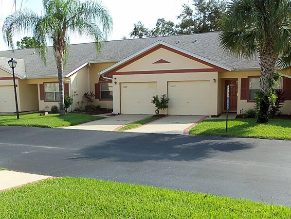 A two-story house with a garage, a front lawn, and a palm tree.