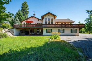 A two-story house with a balcony, a covered porch, and a well-maintained lawn.